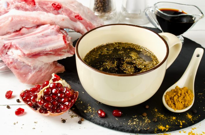 Соус,приправа и гранат возле мяса