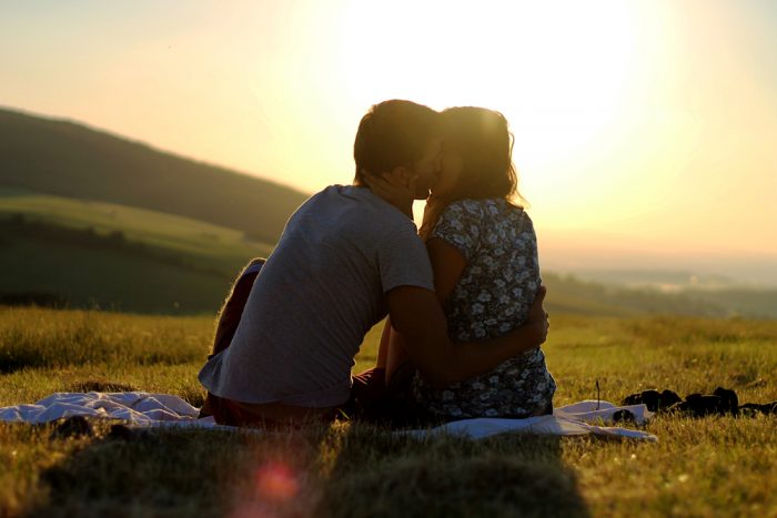 Парень и девушка на природе на закате целуются