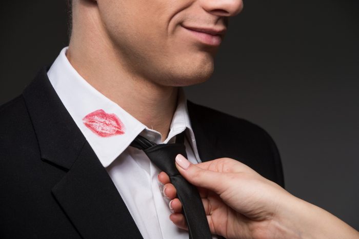 Женская рука поправляет галстук мужчине с помадой на воротнике