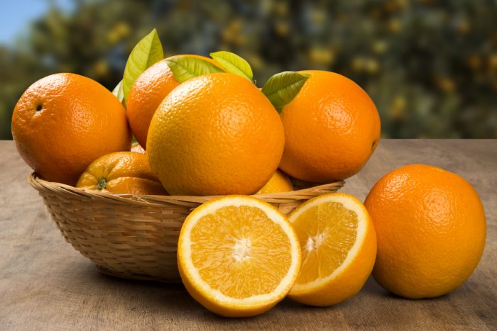 Апельсины в корзинке и на столе половинки