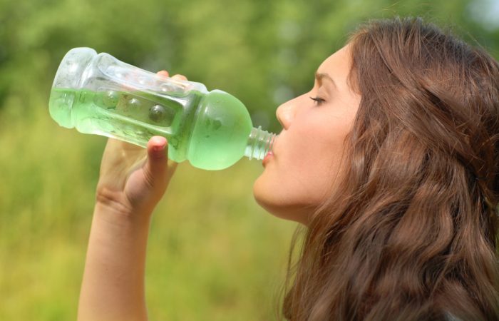 Девушка пьет зеленую газировку из бутылки