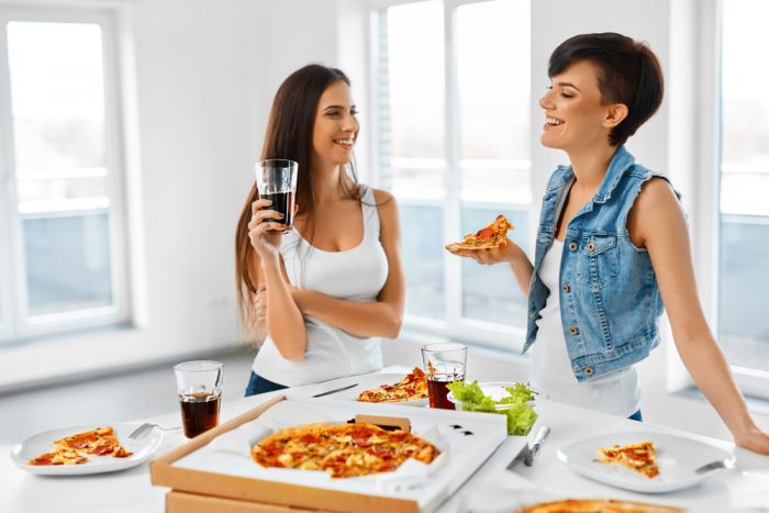 Девушки едят пиццу и пьют газировку