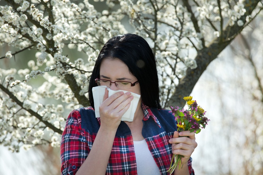 Девушка прикрыла нос из-за аллергии на цветы