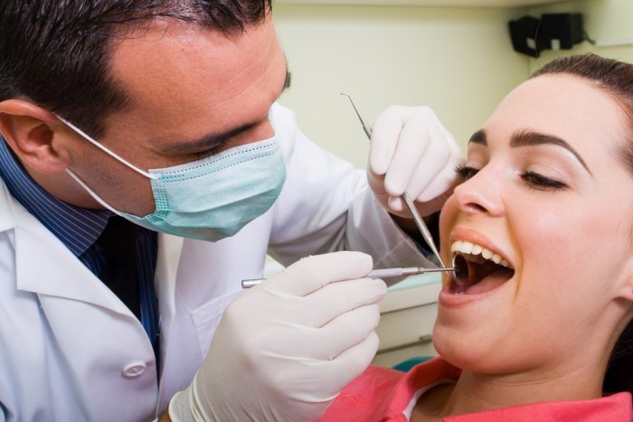 Стоматолог рассматривает зубы у пациентки, которая улыбается