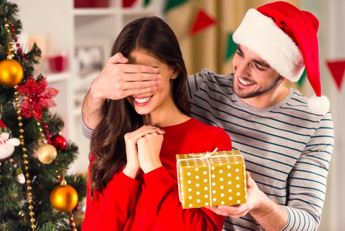 Мужчина дарит подарок на Новый год девушке, закрыв ей глаза