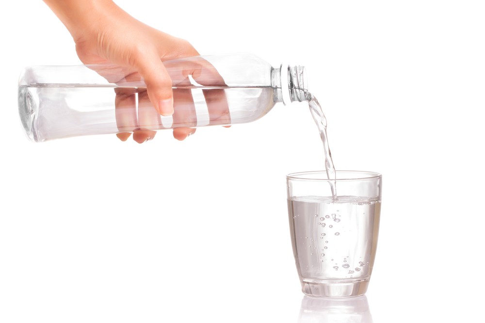 Чистую воду наливают с бутылки в стакан