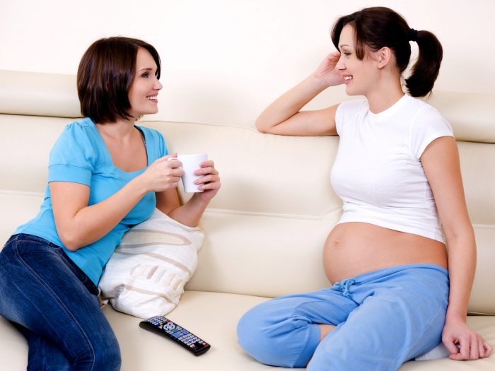 Беременная девушка говорит с подругой