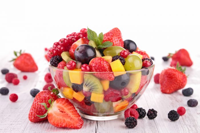 Фруктовый салат из свежих ягод и фруктов в прозрачной тарелке