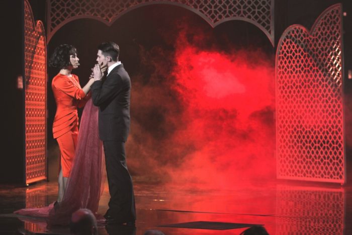 Злата Огневич в красном платье миди с мужчиной на сцене