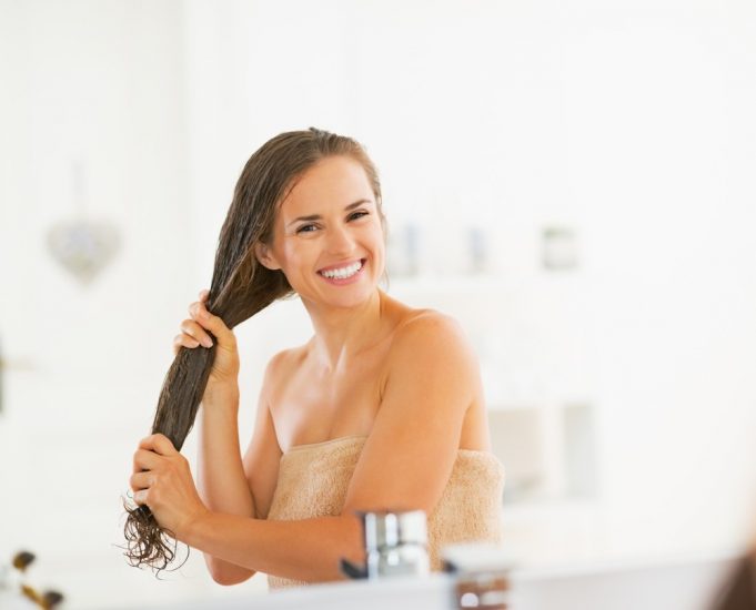 Девушка в полотенце улыбается держась за волосы