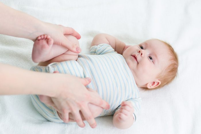 Женские руки держат ребенка за ножки