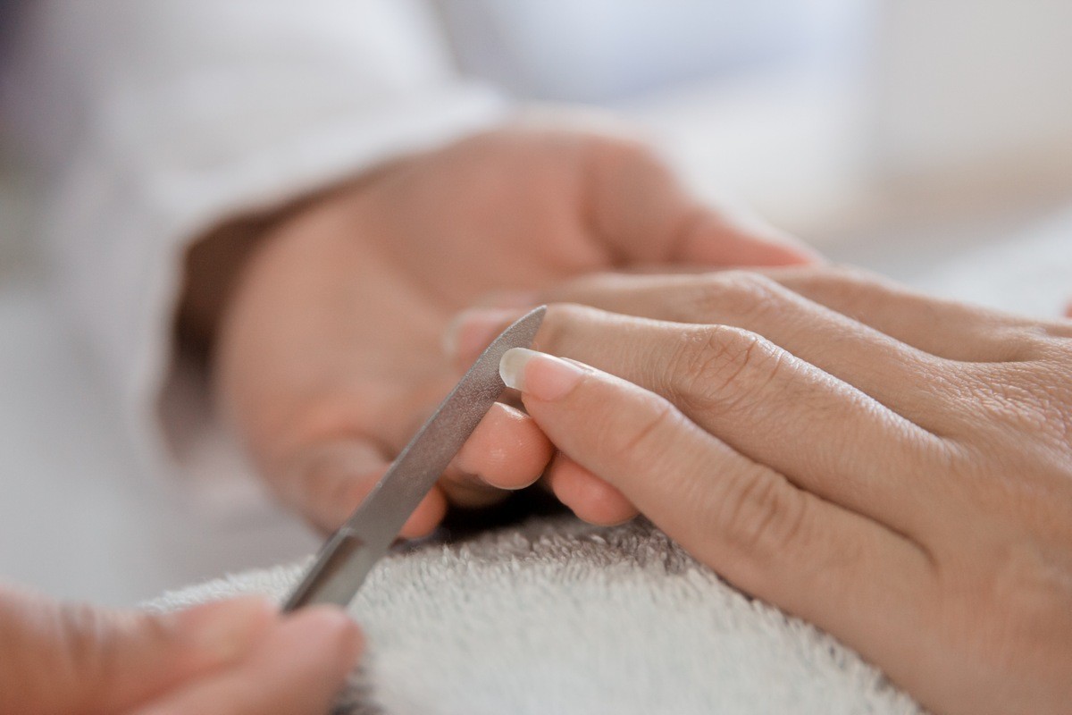 Beautician manicure with nail file in a salon